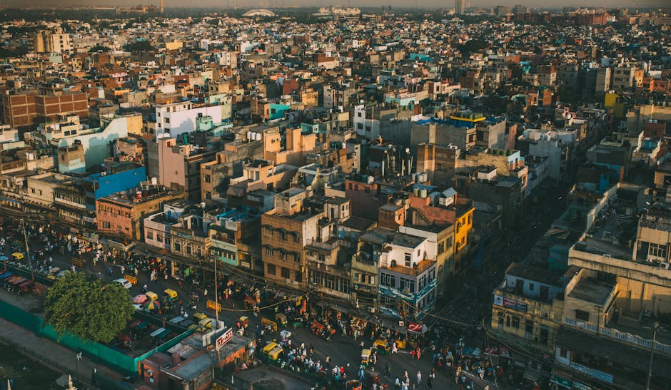 A vibrant aerial cityscape of Delhi, showcasing the bustling streets and diverse architecture under warm daylight.