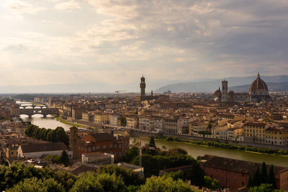 Panoramic view of Florence, Italy featuring the iconic Duomo and Arno River at sunset.