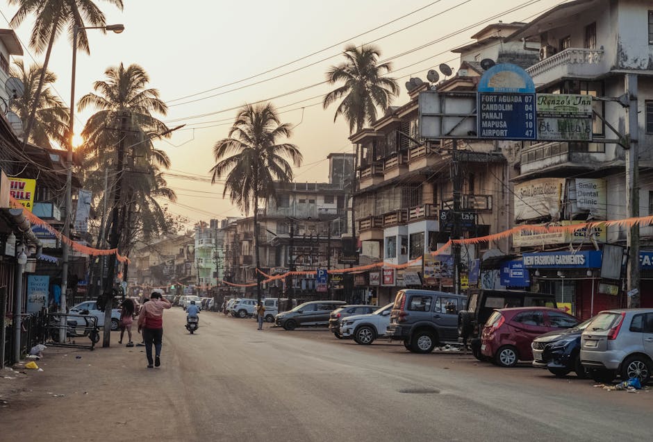 Street scene at sunset in Calangute, India with palm trees and local shops.