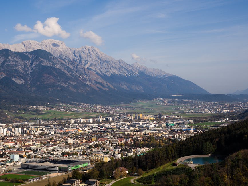 Aerial view of Innsbruck, Austria with the stunning Alps in the background, captured on a clear day.