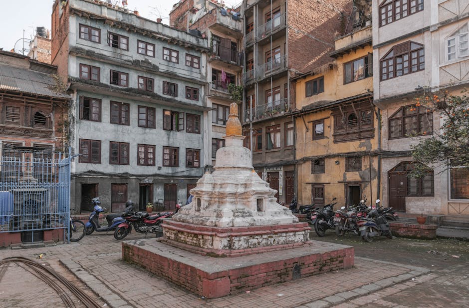 Historic Kathmandu courtyard with stupa and motorbikes, showcasing urban life.