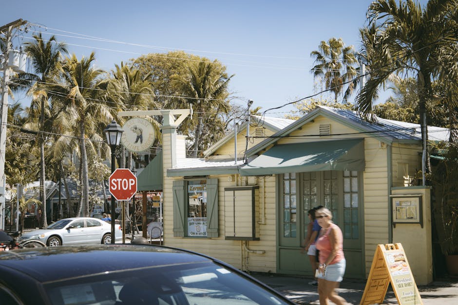 Street scene in Key West, Florida featuring a quaint restaurant, palm trees, and bustling activity.