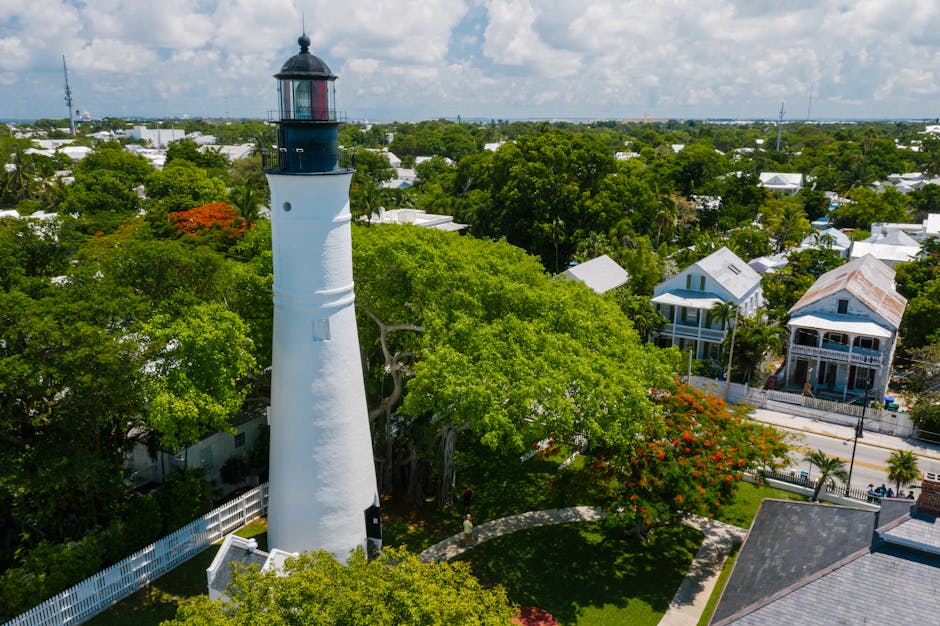 Aerial view of the iconic Key West Lighthouse surrounded by vibrant trees and historic houses.