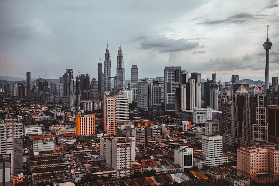 Aerial cityscape of Kuala Lumpur featuring the Petronas Twin Towers and Kuala Lumpur Tower.