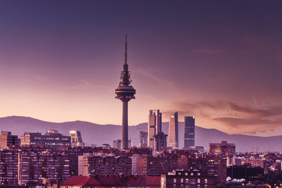 Stunning view of Madrid's skyline at twilight featuring the iconic Torrespaña Tower and mountains in the background.