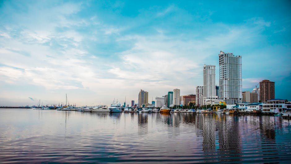 Scenic view of Manila Bay with yachts and city skyline reflecting on calm waters.