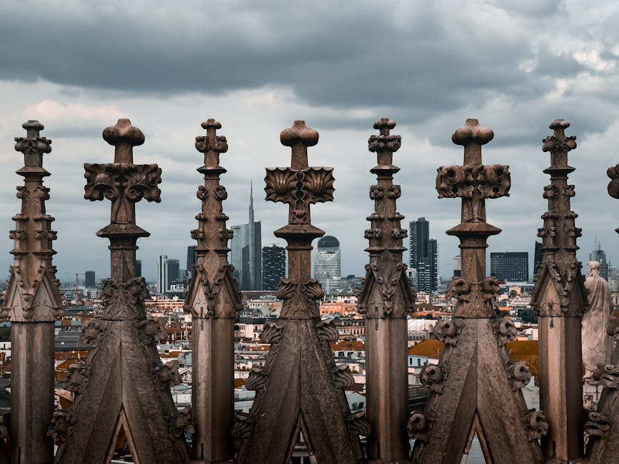 Gothic architecture of Milan Cathedral rooftop with Milan skyline in the background.