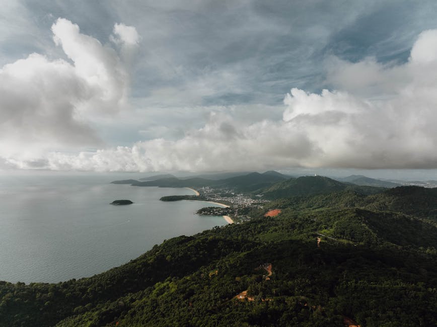 Stunning aerial view of Phuket's lush hills and coastline under a cloudy sky.