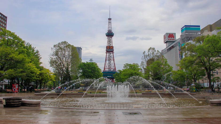 View of the Sapporo TV Tower with fountain in Odori Park, showcasing a spring urban scene.