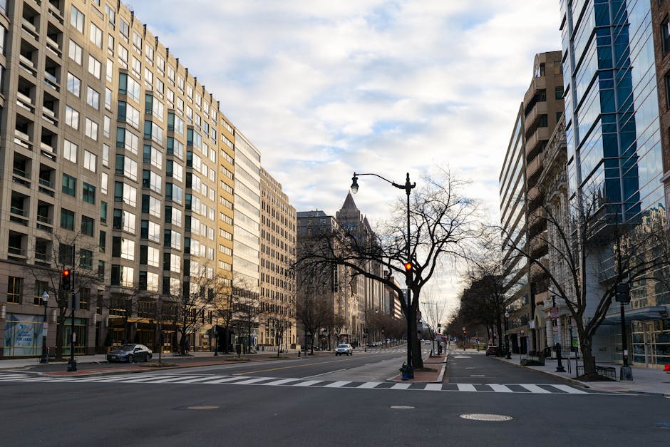 A deserted street in Washington DC showcasing modern urban architecture under a cloudy sky.